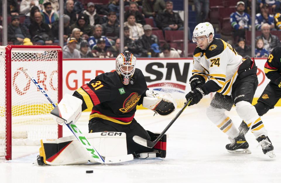 Boston Bruins' Jake DeBrusk (74) tries to get his stick on the loose puck after Vancouver Canucks goalie Arturs Silovs (31) made a pad save during the second period of an NHL hockey game, Saturday, Feb. 25, 2023 in Vancouver, British Columbia. (Rich Lam/The Canadian Press via AP)