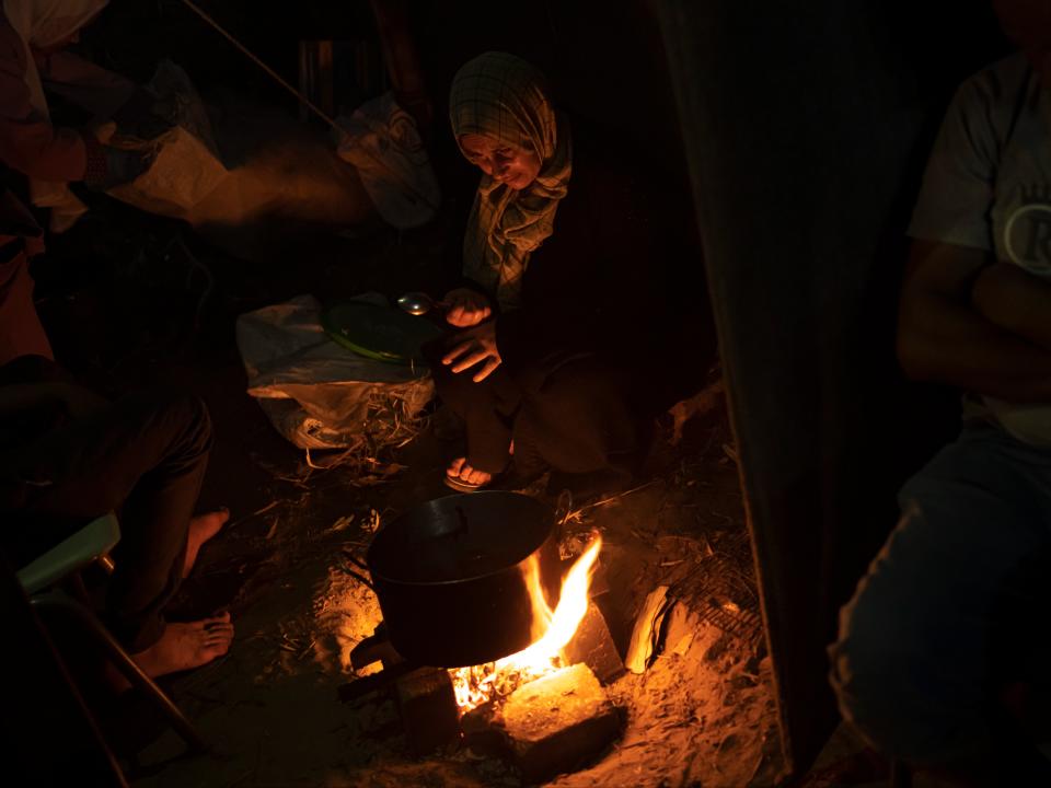 Palestinians displaced by the bombardment sit by a fire (AP)