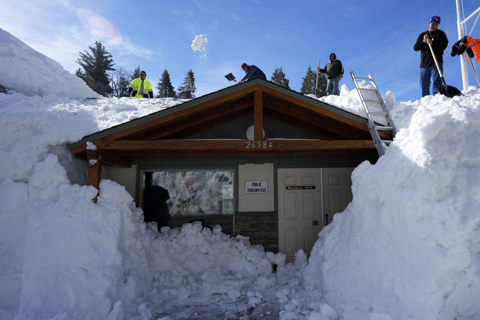 FILE - Workers clear snow off the roof of Skyforest Elks Lodge after a series of storms, March 8, 2023, in Rimforest, Calif. Record snowfall and rain have helped to loosen drought’s grip on parts of the western U.S. as national forecasters and climate experts warned Thursday, March 16, that some areas should expect more flooding as the snow begins to melt. (AP Photo/Marcio Jose Sanchez, File)