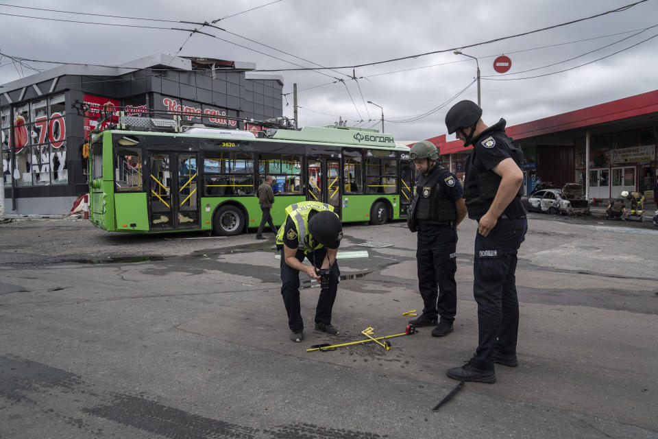 Police officers examine a small crater after a Russian shelling at Barabashovo market in Kharkiv, Ukraine, Thursday, July 21, 2022. (AP Photo/Evgeniy Maloletka)