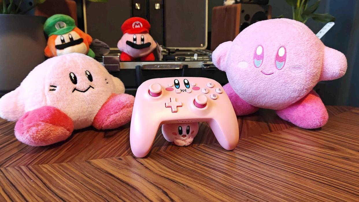  PowerA Kirby controller for Nintendo Switch surrounded by Kirby toys. 