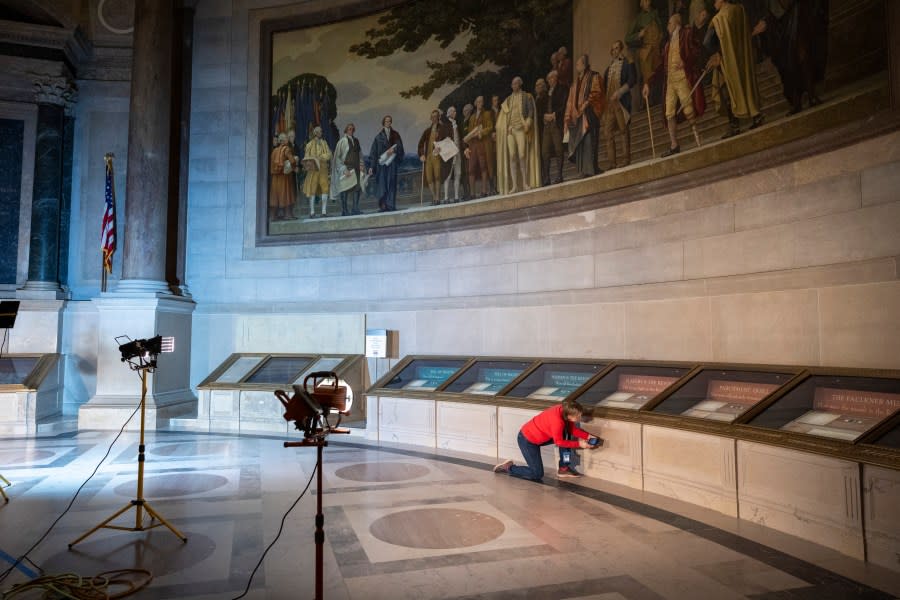 Sarah Stauderman, deputy director of preservation programs at National Archives in Washington, takes a video of a portion of a display case that still has red power on it on Thursday, Feb. 15, 2024. The National Archives building and galleries were evacuated on Feb. 14 after two protesters dumped powder on the protective casing around the U.S. Constitution.(AP Photo/Amanda Andrade-Rhoades)