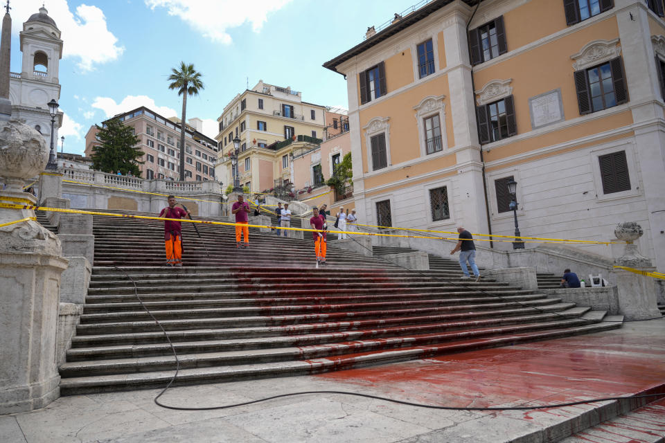 Rome municipality workers clean the Spanish Steps after activists dumped red paint over them protesting against violence on women, in Rome, Wednesday, June 26, 2024. (AP Photo/Andrew Medichini)