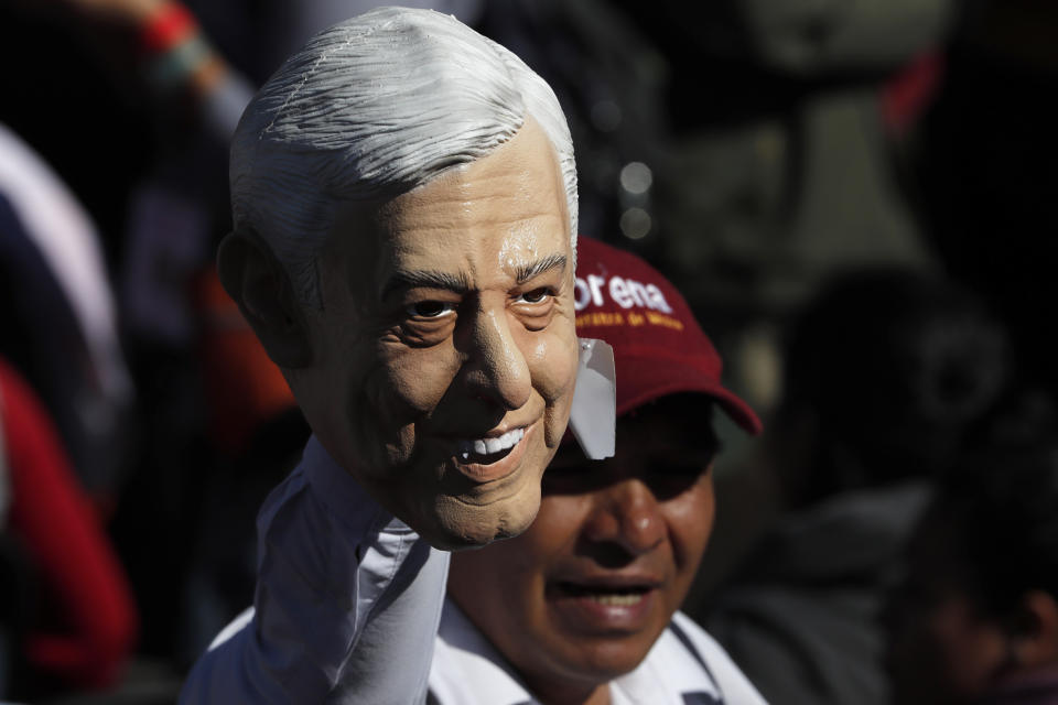 A supporter of Mexico's President Andres Manuel Lopez Obrador holds a rubber mask of Lopez Obrador during a rally to commemorate the President's one year anniversary in office, in Mexico City, Sunday December 1, 2019. Lopez Obrador took office one year ago, vowing to transform Mexico. He has focused on austerity and fighting corruption because corrupt, high-living politicians have angered Mexicans perhaps more than anything else. (AP Photo/Marco Ugarte)