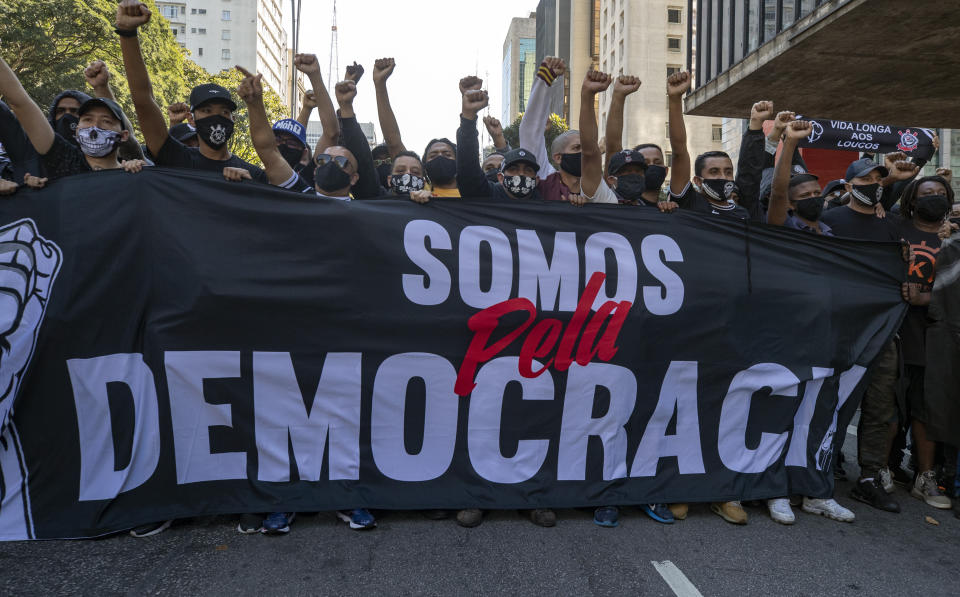 Aficionados de dos clubes de fútbol sostienen una pancarta que dice en portugués "Estamos a favor de la democracia", al unir fuerzas para una protesta contra el gobierno en Sao Paulo, Brasil, el domingo 31 de mayo de 2020. (Foto AP/Andre Penner)