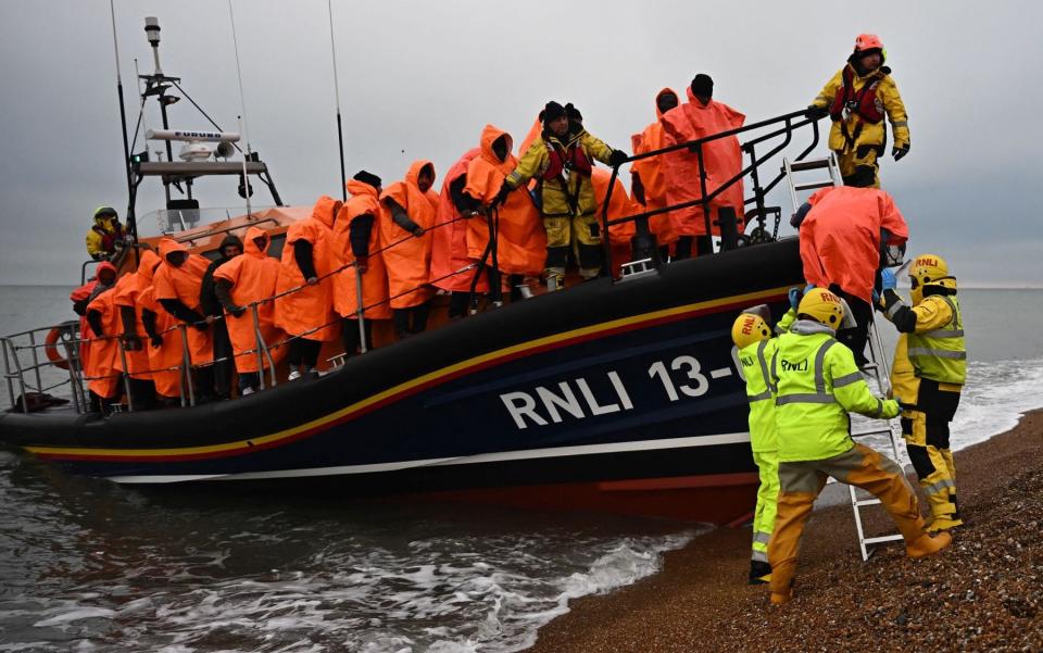 Migrants picked up at sea attempting to cross the English Channel are helped ashore from an RNLI lifeboat at Dungeness - BEN STANSALL/AFP