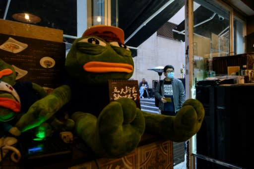 Diners slurp wonton under the watchful gaze of a gas mask-wearing Pepe the Frog, which has become a mascot of the pro-democracy movement