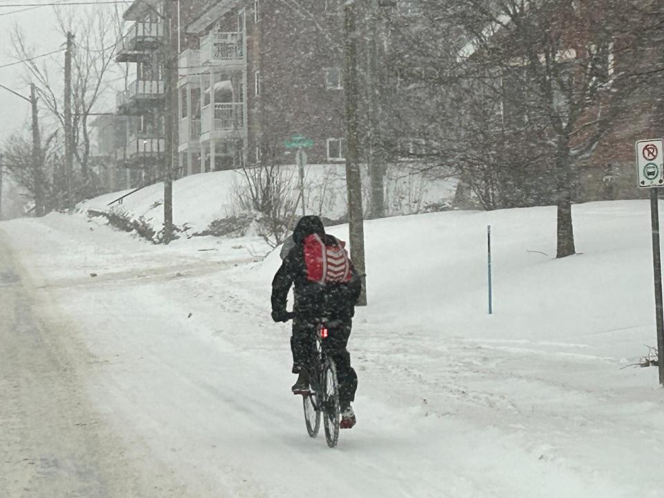 A cyclist takes to the snowy Moncton streets. Late Wednesday morning, snow is expected to transition to ice pellets and then rain.