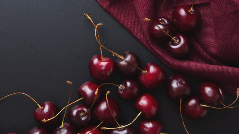 Fresh cherries against a dark wine-colored background