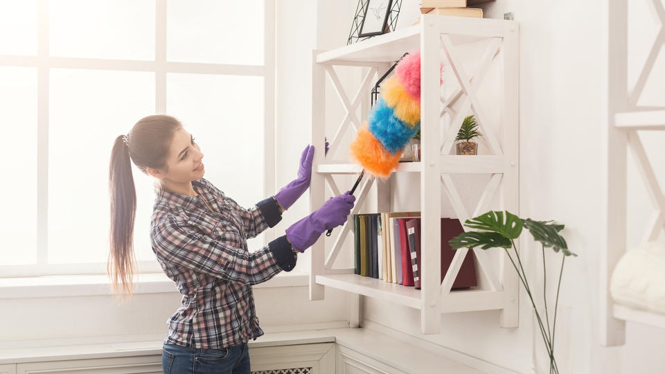 Woman dusting a wall-hung shelf