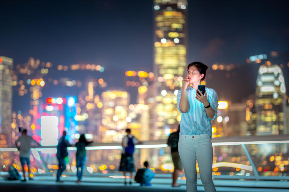 A woman uses her smartphone at Hong Kong's Victoria Harbor.