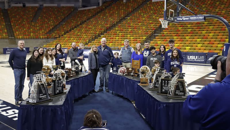 Stew and Vicki Morrill and their family pose for photos with trophies from Morrill’s coaching tenure at Utah State Friday night at the Spectrum in Logan.