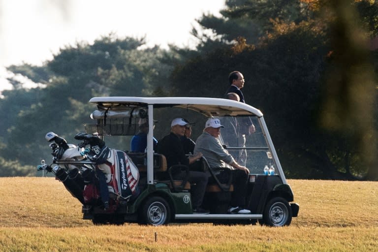 US President Donald Trump (front R) and Japanese Prime Minister Shinzo Abe (front L) return in a golf cart after playing a round