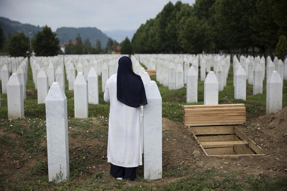 A woman prays near a grave of a family member in the Memorial centre in Potocari, Bosnia, Friday, July 8, 2022. After surviving the 1995 Srebrenica massacre in which over 8,000 of their male relatives were killed, women from the small town in eastern Bosnia dedicated the remaining years of their lives to the re-telling of their trauma to the World, honoring the victims and bringing those responsible for the killings to justice. (AP Photo/Armin Durgut)