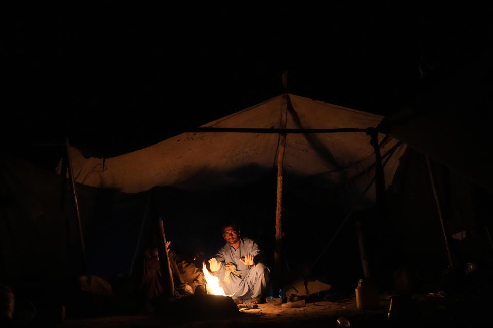 Afghan warms himself in a makeshift shelter after an earthquake in Gayan district in Paktika province, Afghanistan, Saturday, June 25, 2022. A powerful earthquake struck a rugged, mountainous region of eastern Afghanistan early Wednesday, flattening stone and mud-brick homes in the country's deadliest quake in two decades, the state-run news agency reported. (AP Photo/Ebrahim Nooroozi)