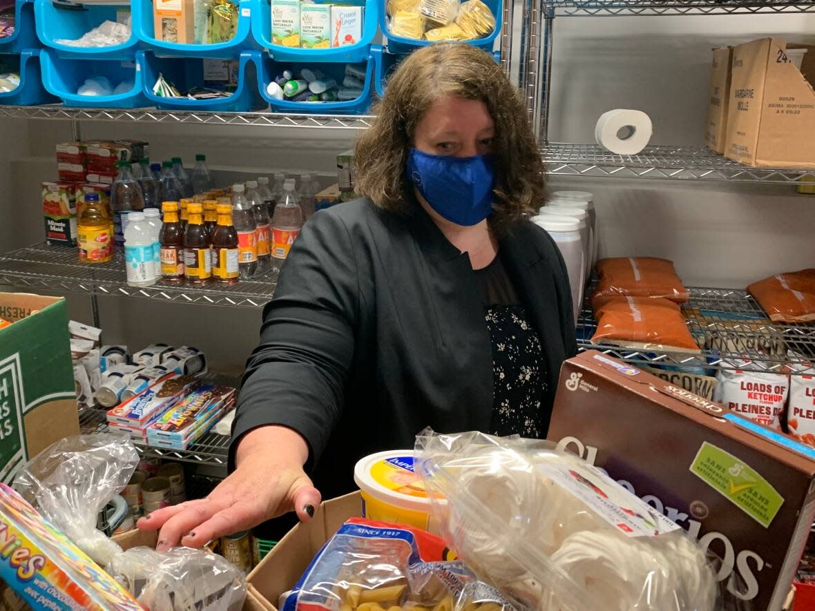 Kerri Abbott examines daily hampers being prepared for people in the Carbonear region. She said with the rising fuel costs, some people are facing challenges to get the food they need.  (Adam Walsh/CBC - image credit)