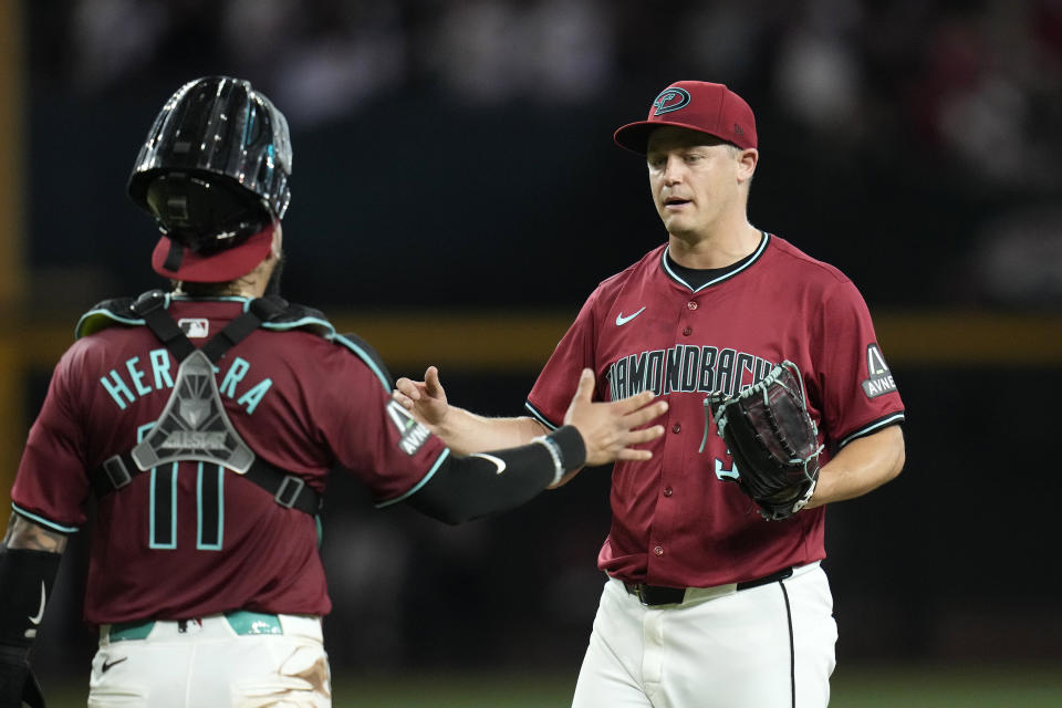 Arizona Diamondbacks relief pitcher Paul Sewald, right, slaps hands with catcher Jose Herrera, left, after the final out of a baseball game against the Oakland Athletics, Saturday, June 29, 2024, in Phoenix. The Diamondbacks won 3-0. (AP Photo/Ross D. Franklin)