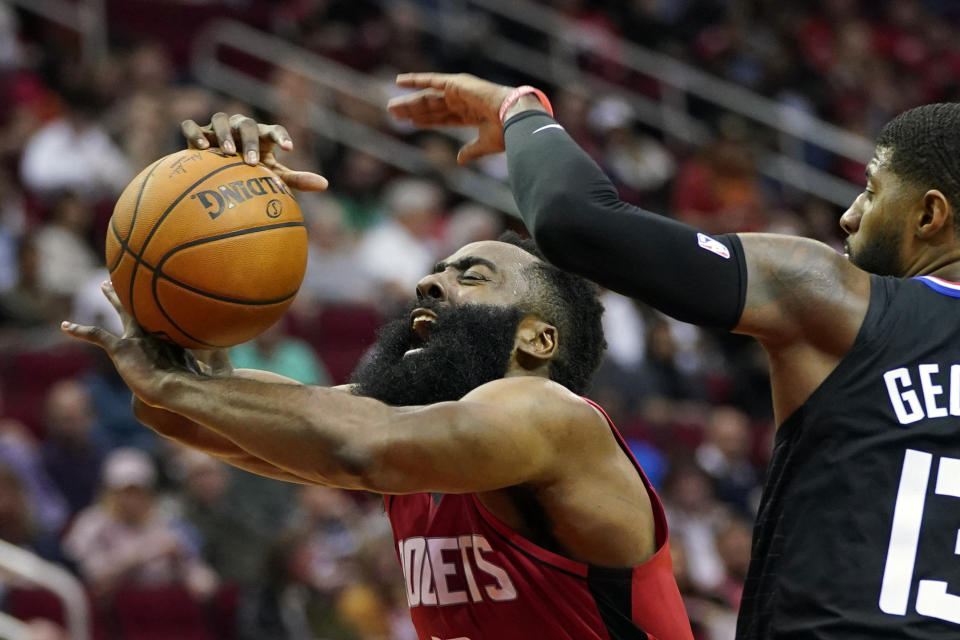 FILE - In this March 5, 2020, file photo, Houston Rockets' James Harden, left, is fouled by Los Angeles Clippers' Paul George during the second half of an NBA basketball game in Houston. The photo was part of a series of images by photographer David J. Phillip which won the Thomas V. diLustro best portfolio award for 2020 given out by the Associated Press Sports Editors during their annual winter meeting. (AP Photo/David J. Phillip, File)