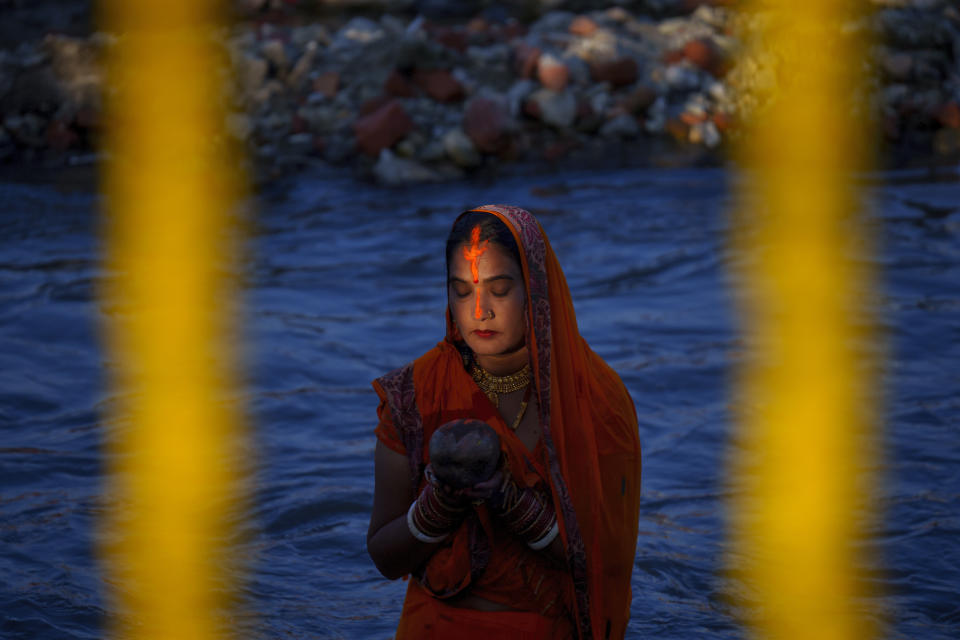 A Nepalese woman offers prayers to the setting sun at the Bagmati River during the Chhath Puja festival in Kathmandu, Nepal, Sunday, Oct. 30, 2022. (AP Photo/Niranjan Shrestha)