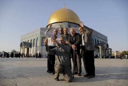 Palestinian Hussam Abu Daba'a (C), 55, from the West Bank city of Hebron, takes a selfie photo with friends and relatives in front of the Dome of the Rock on the compound known to Muslims as Noble Sanctuary and to Jews as Temple Mount, in Jerusalem's Old City, during the holy month of Ramadan, July 1, 2015. REUTERS/Ammar Awad