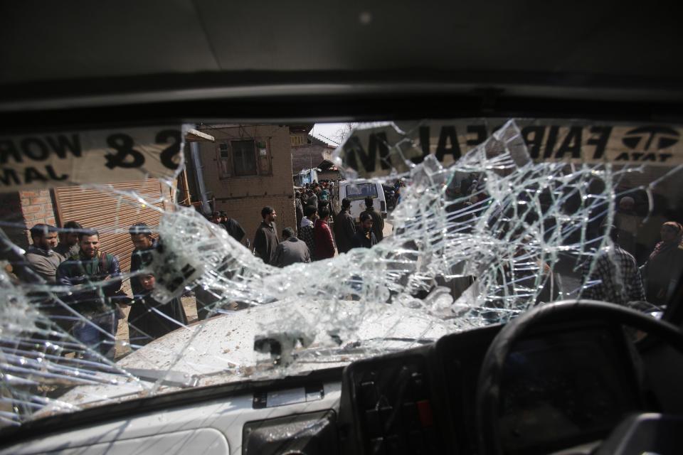 Kashmiri men are seen through the damaged windshield of a vehicle after a shootout in Moul village, 62 kilometers (39 miles) south of Srinagar, Indian controlled Kashmir, Thursday, Feb.23, 2017. Three Indian soldiers and a woman were killed after rebels ambushed soldiers in the disputed region of Kashmir, police said on Thursday. Locals said that shortly after the firing stopped, soldiers ransacked homes and smashed dozens of cars in the area. Indian army and police did not immediately respond to the allegations.(AP Photo/Mukhtar Khan)