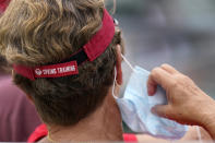 A baseball fan briefly removes a protective face mask while watching a spring training game between the Washington Nationals and St. Louis Cardinals Sunday, Feb. 28, 2021, in Jupiter, Fla. (AP Photo/Jeff Roberson)