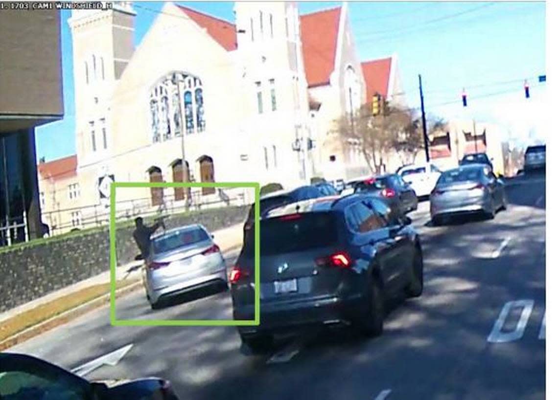A screen capture of Arlo Smith, then 17, hanging out of a stolen silver Hyundai firing an AR-style pistol over traffic in downtown Durham on Dec. 3, 2019.