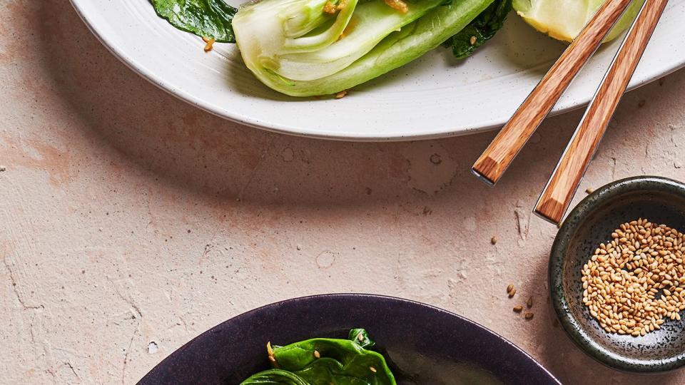 bok choy topped with ginger and sesame seeds in a black bowl