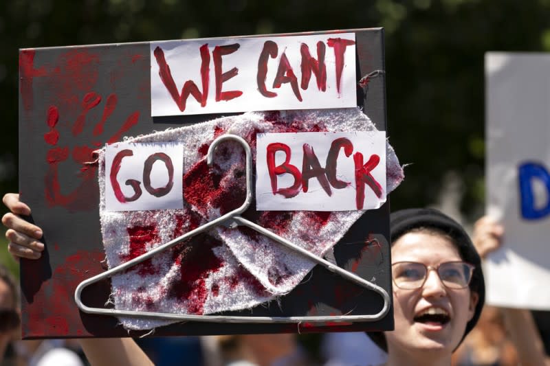 反對取消墮胎權的女性在抗議時高舉「我們不能倒退」的標語，上頭還有過去自行墮胎常見的「工具」—衣架、以及斑斑血跡。（美聯社）