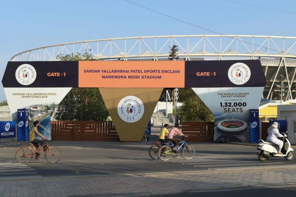 Cyclists cycle past the main entrance of the Narendra Modi Stadium, a venue where cricket matches were taking place during the 2021 Indian Premier League (IPL), in Motera on 4 May 2021 following IPL's decision to suspend the tournament for safety reasons as India battled a massive surge in coronavirus cases (AFP via Getty Images)