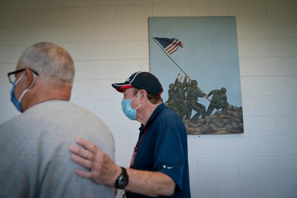 Gary Powell, 69, of Detroit, left, an Army National Guard veteran who is homeless, is taken to get supplies that include toiletries and clothes by Michigan Veterans Foundation support staff Lester Goins Tuesday, Aug. 29, 2023, in Detroit. The two walk past a painting of a famous photo taken by Joe Rosenthal of U.S. Marines raising an American Flag on the Japanese Island of Iwo Jima in 1945. Staff at the Michigan Veterans Foundation in Detroit work hard the whole year round to make life better for veterans who rely on their services.
