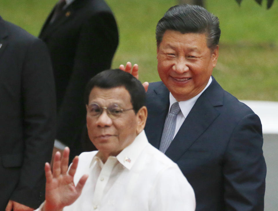 FILE - In this Tuesday, Nov. 20, 2018, file photo, Chinese President Xi Jinping, right, and Philippine President Rodrigo Duterte wave to the media following a welcome ceremony at Malacanang Palace in Manila, Philippines. During Xi’s visit the Philippines, the sides signed a "memorandum of understanding on cooperation on oil and gas development," but officials provided few details. Ahead of Xi's visit, China and the Philippines tried to negotiate an agreement allowing joint oil and gas exploration in the disputed waters. No consensus appeared to have been reached. (AP Photo/Bullit Marquez)