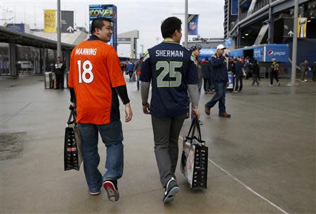 A Denver Broncos fan (L) walks with a Seattle Seahawks fan outside the stadium before the start of the NFL Super Bowl XLVIII football game in East Rutherford, New Jersey, February 2, 2014. REUTERS/Shannon Stapleton