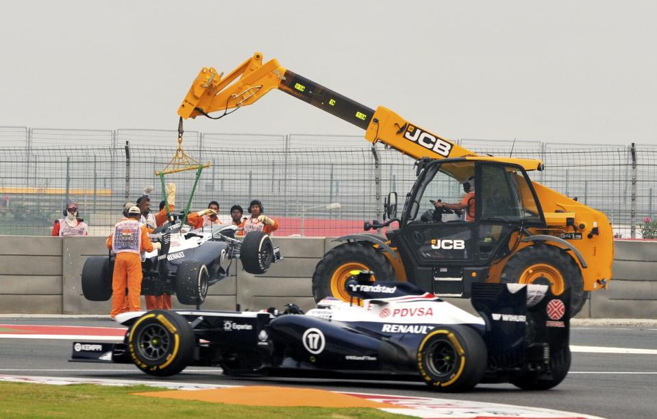 Williams Formula One driver Valtteri Bottas of Finland drives past as the car of Williams Formula One driver Pastor Maldonado of Venezuela is lifted during the second practice session of the Indian F1 Grand Prix at the Buddh International Circuit in Greater Noida, on the outskirts of New Delhi, October 25, 2013. REUTERS/Stringer (INDIA - Tags: SPORT MOTORSPORT F1) NO ARCHIVES.