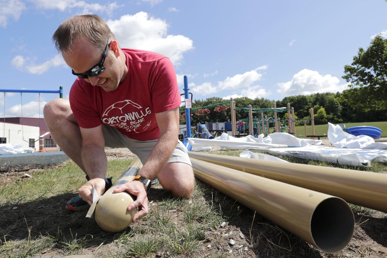 Volunteer David Reynolds sands posts that will be anchor points for a swingset on a new playground at Hortonville Elementary School in August 2023.
