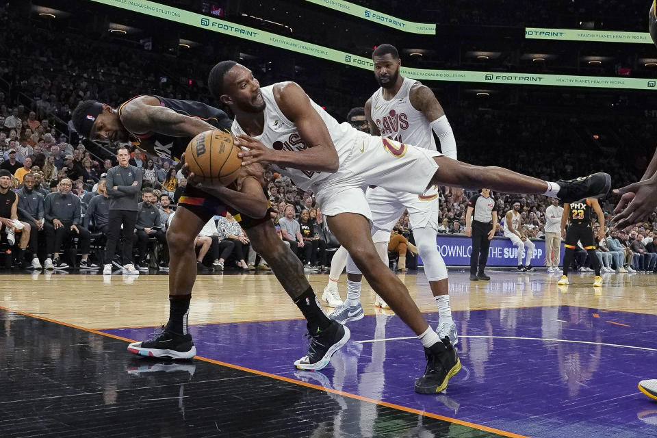 Cleveland Cavaliers forward Evan Mobley saves the ball from going out of bounds, next to Phoenix Suns guard Bradley Beal, left, during the first half of an NBA basketball game in Phoenix, Wednesday, April. 3, 2024. (AP Photo/Darryl Webb)
