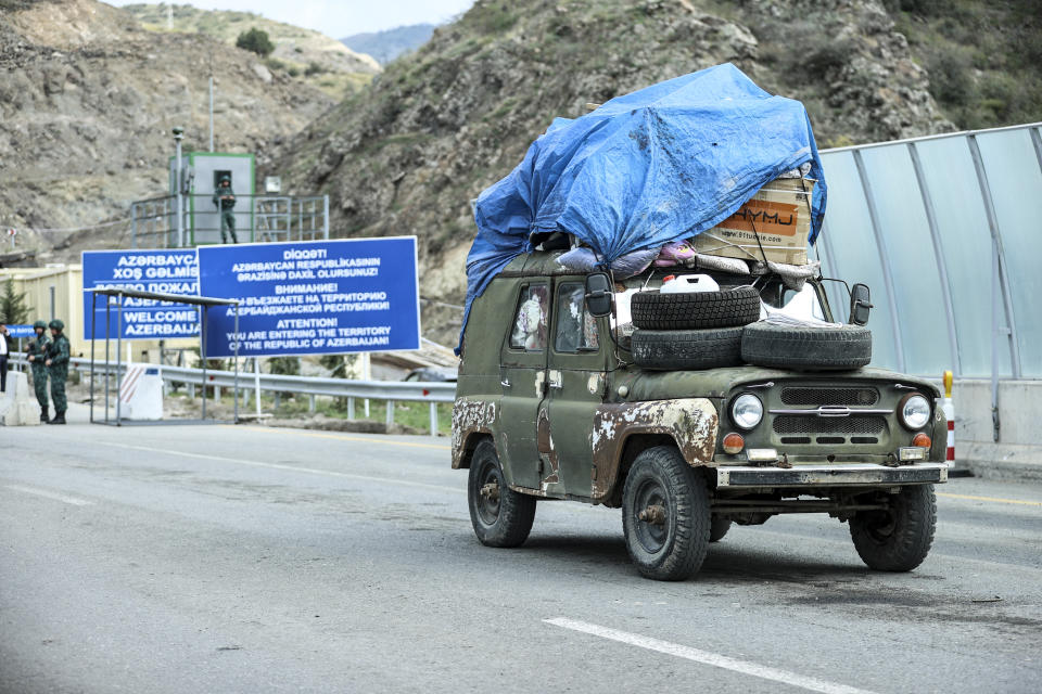 Sergey Astsetryan, an ethnic Armenian resident of Nagorno-Karabakh, drives his Soviet-made vehicle past Azerbaijani border guard servicemen after been checked at the Lachin checkpoint on the way from Nagorno-Karabakh to Armenia, in Azerbaijan, Sunday, Oct. 1, 2023. Astsetrayn was one of the last residents of Nagorno-Karabakh to drive out of the region in his own vehicle as part of a grueling weeklong exodus of over 100,000 people — more than 80% of the residents — after Azerbaijan reclaimed the area in a lightning military operation. (AP Photo/Aziz Karimov)