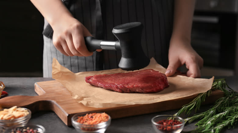 woman beating steak with tenderizer