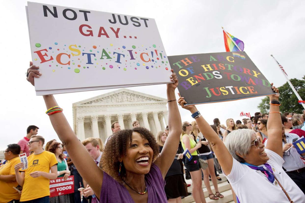 Ikeita Cantu, left, and her wife Carmen Guzman, of McLean, Va., hold up signs as they celebrate outside of the Supreme Court in Washington, Friday June 26, 2015, after the court declared that same-sex couples have a right to marry anywhere in the US. The couple was married in Canada in 2009 when gay marriage was illegal in Virginia