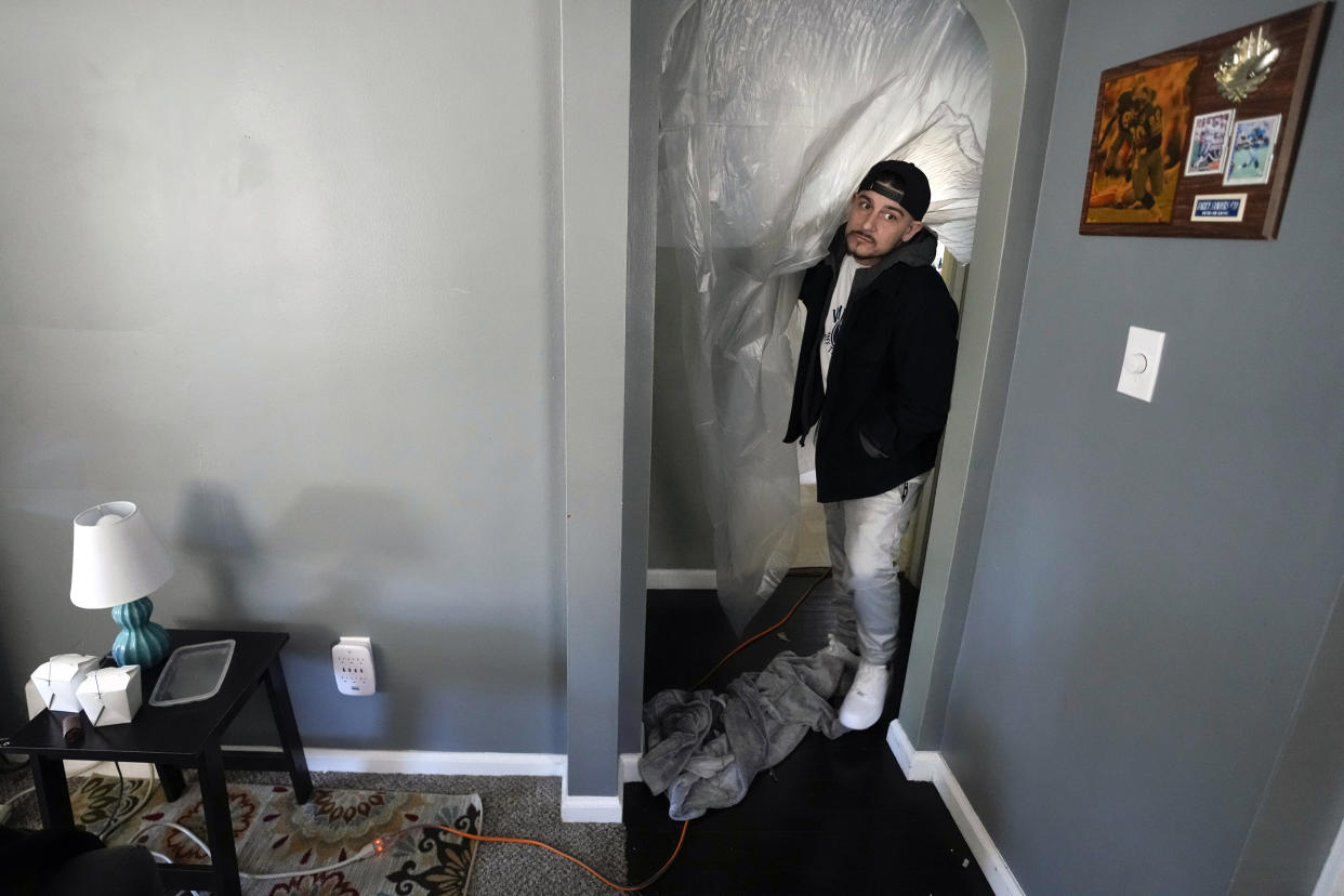 Mitch Wengrzynowicz uses plastic to try and keep rooms warm as his home lost power in Dearborn, Mich., Friday, Feb. 24, 2023. Michigan is shivering through extended power outages caused by one of the worst ice storms in decades. (AP Photo/Paul Sancya)