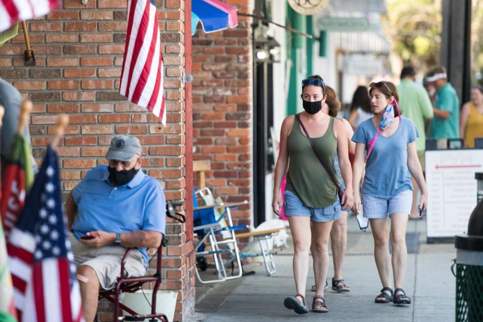 People walk down the sidewalk in St Simons Island, Georgia, on 17 July. Brian Kemp made an order earlier in the week that forbade municipal officials from setting mandatory face-covering policies.