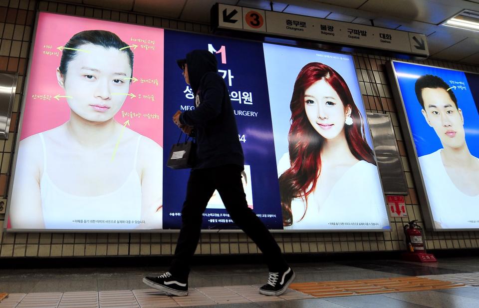 A pedestrian walks past advertisements for plastic surgery clinics at a subway station in Seoul in March 2014.<span class="copyright">Jung Yeon-je—AFP/Getty Images</span>