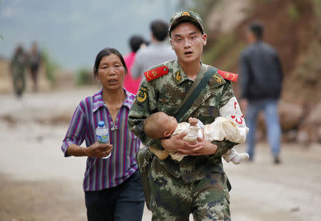 A paramilitary policeman carries a baby in his arms after an earthquake hit Ludian county of Zhaotong, Yunnan province August 3, 2014. REUTERS/China Daily