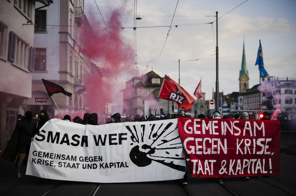 Protesters walk with banners reading "Smash WEF" during a demonstration against the World Economic Forum (WEF) in Zurich, Switzerland, Friday, May 20, 2022. The World Economic Forum Annual Meeting will take place from May 22-26, in Davos. (Michael Buholzer/Keystone via AP)