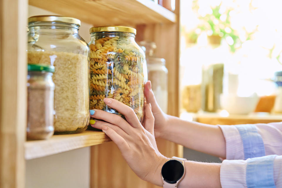 hands storing a jar of dry pasta on the shelf