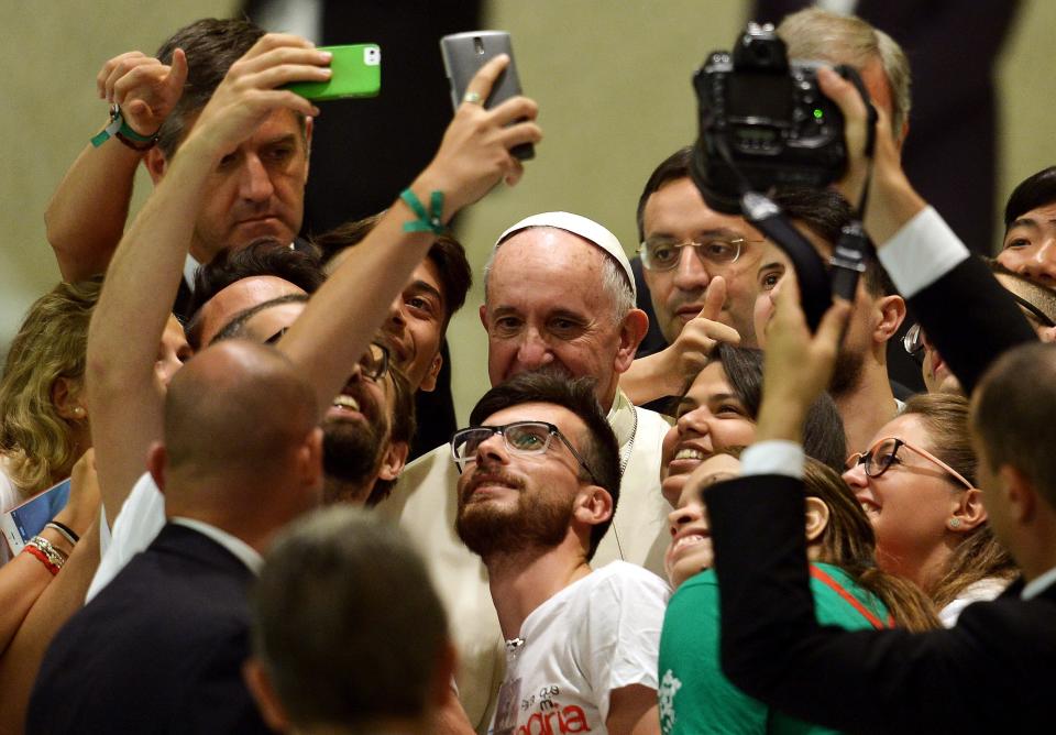 Pope Francis takes a selfie with a group of people during a meeting with the Youth Eucharistic Movement in the Paul VI hall at the Vatican on August 7, 2015. AFP PHOTO / FILIPPO MONTEFORTE        (Photo credit should read FILIPPO MONTEFORTE/AFP/Getty Images)