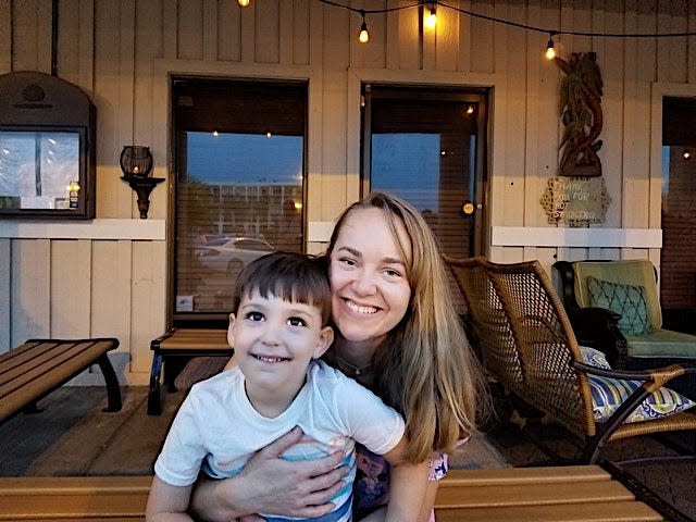 Ashley Archambault and her son smiling at the camera sitting on a porch.