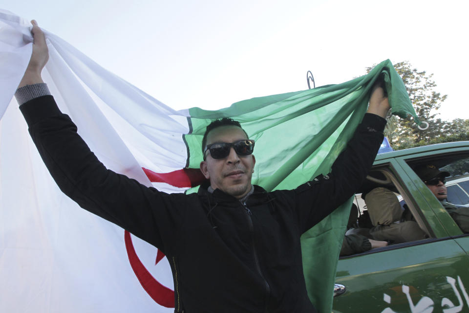A man holds the national flag during the funeral of late Algerian military chief Gaid Saleh in Algiers, Algeria, Wednesday, Dec. 25, 2019. Algeria is holding an elaborate military funeral for the general who was the de facto ruler of the gas-rich country amid political turmoil throughout this year. (AP Photo/Fateh Guidoum)