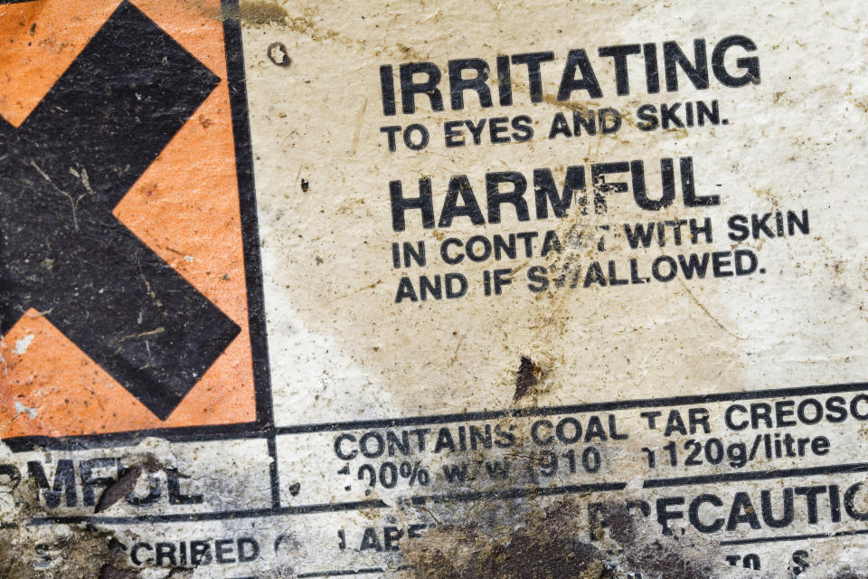 A warning sign letting people know it "contains coal tar creosote"