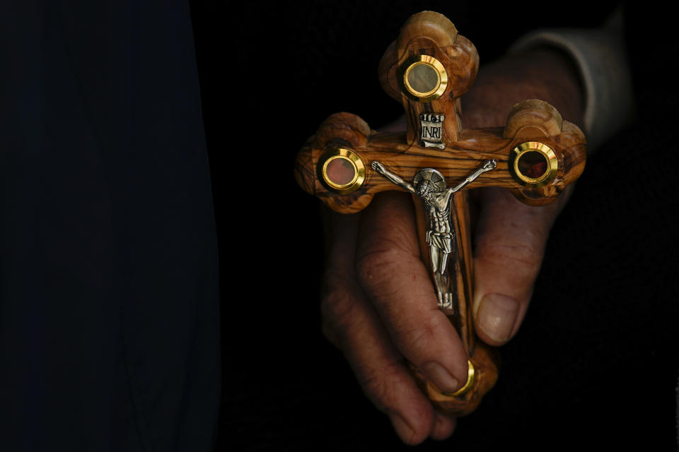 An Orthodox Christian worshipper holds a cross during a Good Friday procession at the Church of the Holy Sepulcher, where many Christians believe Jesus was crucified, buried and rose from the dead, in Jerusalem's Old City, Friday, April 14, 2023. (AP Photo/Ariel Schalit)